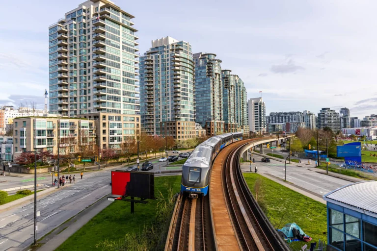 Een skytrain rijdt op verhoogd spoor tussen hoge appartementengebouwen in het centrum van Vancouver