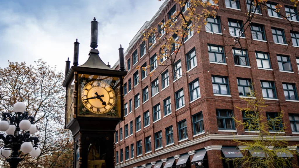 Close-up van de historische gouden stoomklok in de wijk Gastown in Vancouver, met op de achtergrond een bakstenen gebouw