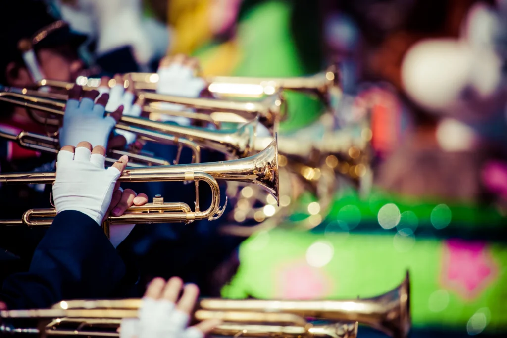 Close-up van glimmende trompetten en witte handschoenen van muzikanten in een marchingband tijdens een kleurrijke optocht