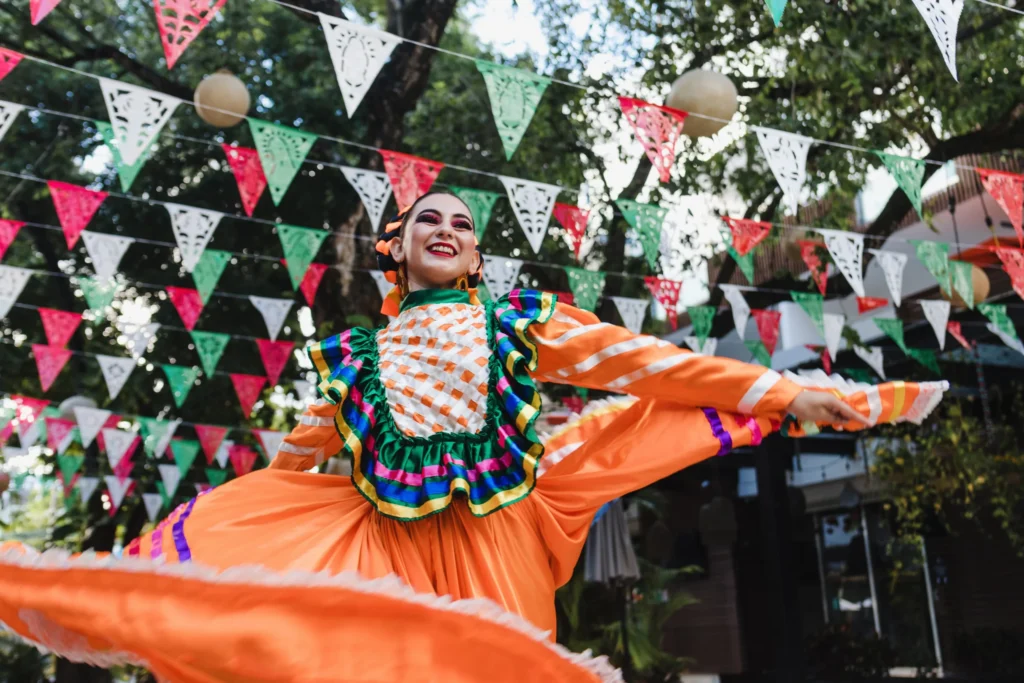 Lachende danseres in een felgekleurde oranje jurk draait rond onder papieren vlaggetjes tijdens een straatfeest