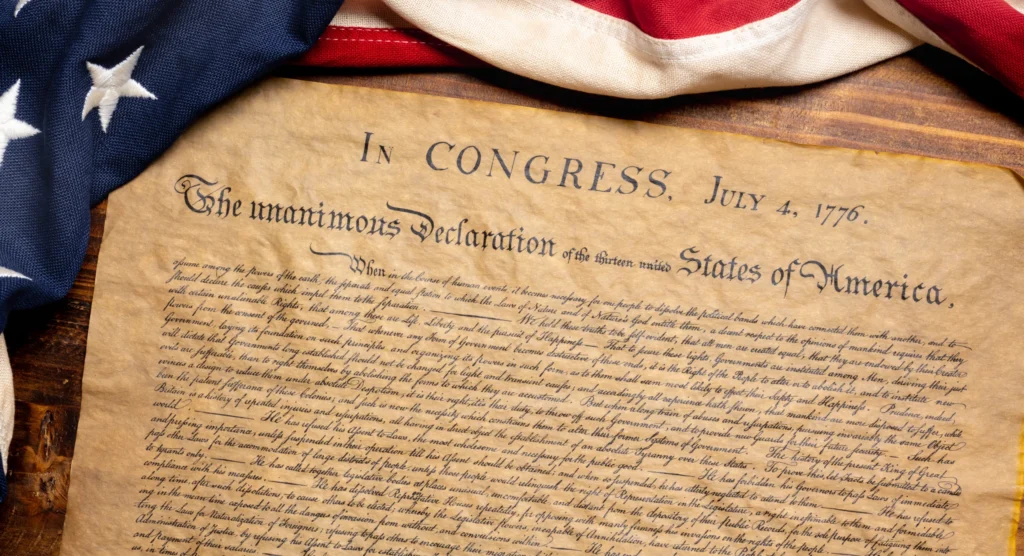 Vergeeld document met de tekst van de onafhankelijkheidsverklaring van 4 juli 1776 gedeeltelijk bedekt door een Amerikaanse vlag