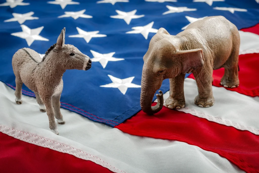 Kleine speelgoedfiguren van een ezel en een olifant tegenover elkaar op een Amerikaanse vlag als symbool van de twee partijen