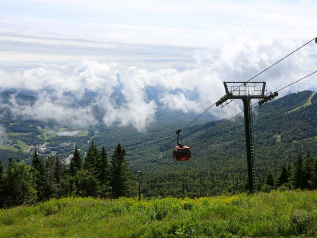 Rode gondelcabine van een kabelbaan hangt boven een uitgestrekt bos met wolken in de vallei op de achtergrond in Vermont