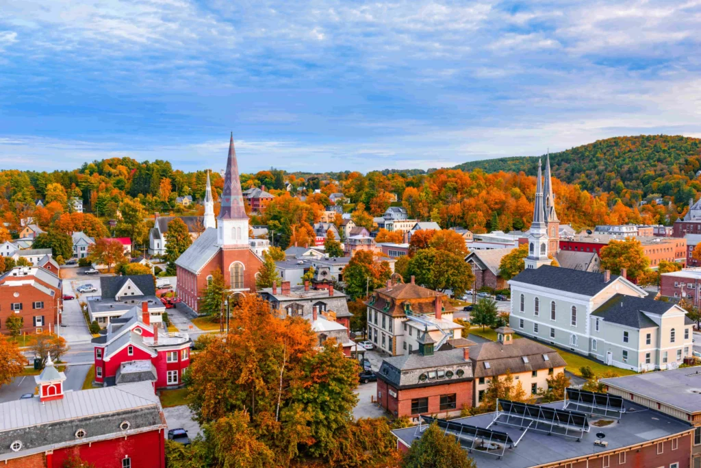 Luchtfoto van een klein stadje in Vermont met kerktorens en huizen omringd door bomen in felle herfstkleuren