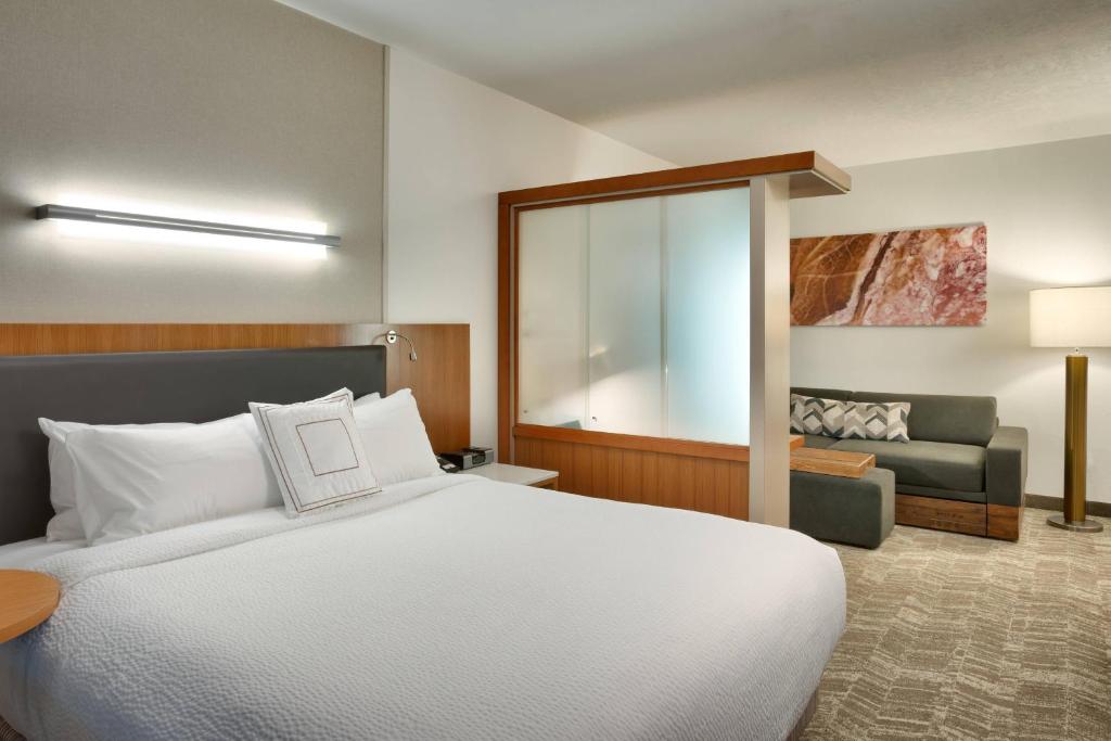 Moderne hotelkamer met een tweepersoonsbed, een glazen scheidingswand en een kleine zithoek met bank