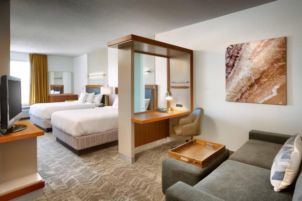 Hotelkamer met twee opgemaakte bedden, een abstract kunstwerk aan de wand en een televisie op een ladekast