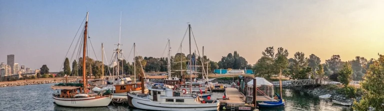 Diverse zeilboten en vissersboten liggen afgemeerd in de haven van Victoria terwijl de zon ondergaat
