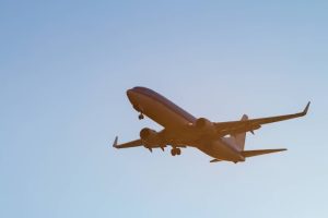 Vliegtuig van onderaf gefotografeerd terwijl het door een lichtbewolkte lucht vliegt