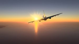 Silhouet van een vliegtuig dat recht op de ondergaande zon af vliegt boven een uitgestrekte oceaan met een kustlijn in de verte