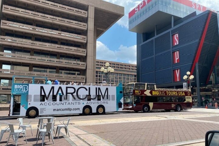 Twee dubbeldekker sightseeingbussen staan geparkeerd voor het opvallende gebouw van het International Spy Museum