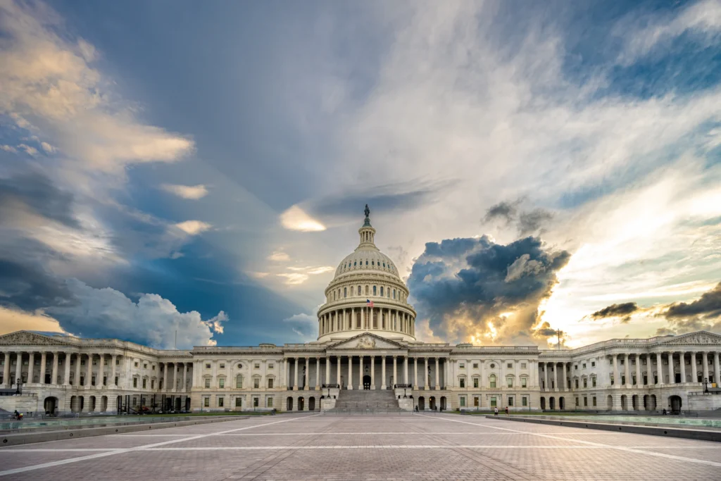 Het witte Capitool met koepel gefotografeerd van voren onder een dramatische lucht met zon en donkere wolken in Washington DC