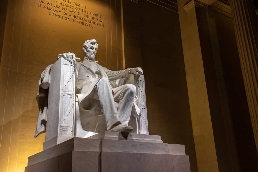 Marmeren zittend standbeeld van Abraham Lincoln in het Lincoln Memorial met een ingemetselde tekst op de muur erachter