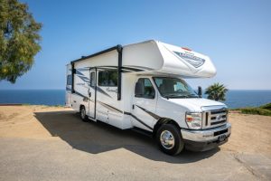 Een witte camper staat geparkeerd op een uitzichtpunt aan de kust van West-Amerika met de oceaan op de achtergrond