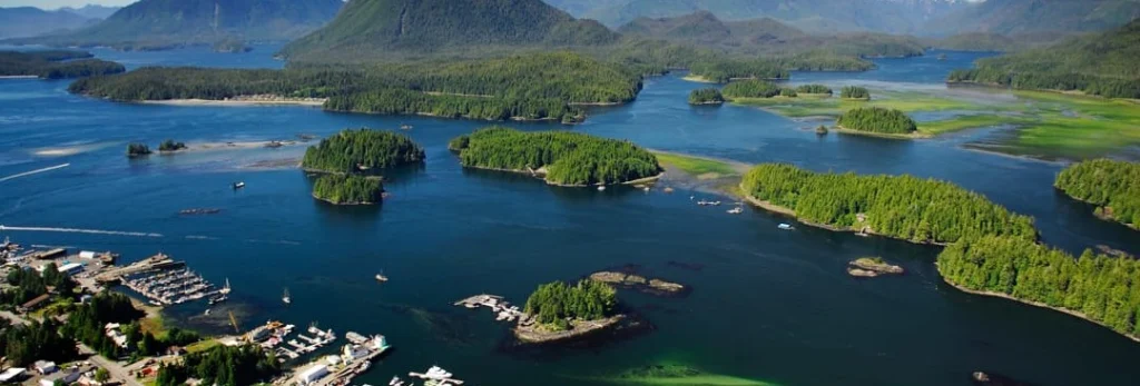 Luchtfoto van talloze begroeide eilandjes verspreid in een blauwe baai met bergen op de achtergrond in West-Canada
