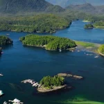 Luchtfoto van talloze begroeide eilandjes verspreid in een blauwe baai met bergen op de achtergrond in West-Canada