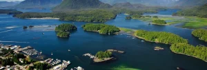 Luchtfoto van talloze begroeide eilandjes verspreid in een blauwe baai met bergen op de achtergrond in West-Canada