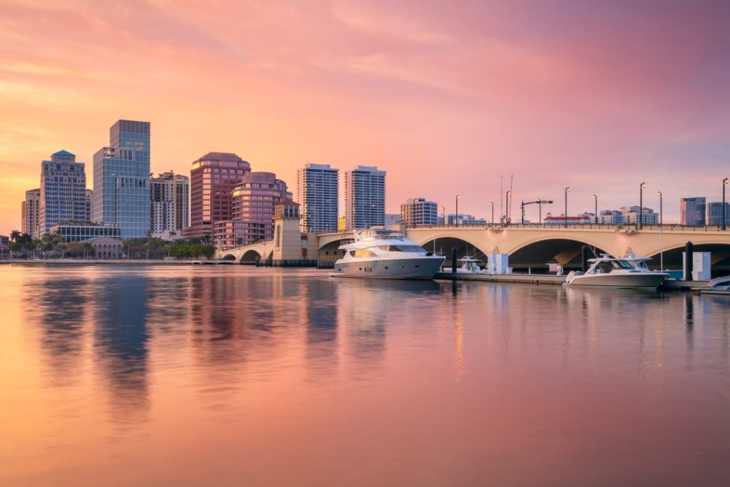 Wolkenkrabbers van West Palm Beach en een brug kleuren roze bij zonsondergang, met jachten afgemeerd in het water