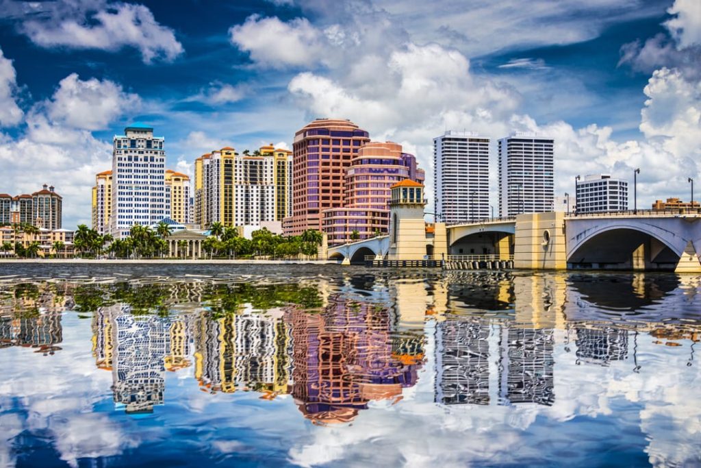 Wolkenkrabbers en een brug van West Palm Beach weerspiegelen in kalm water onder een bewolkte lucht