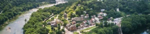 Vanuit de lucht gezien liggen kleine huizen en een kerktoren tussen dicht bos aan een brede rivier in West Virginia