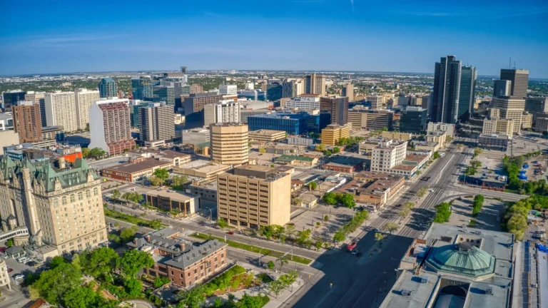 Luchtfoto van hoogbouw en straten in het centrum van Winnipeg onder een heldere blauwe lucht