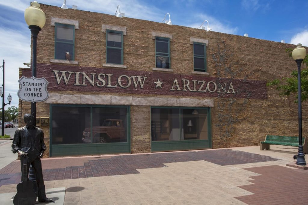 Bronzen standbeeld van een gitarist op de hoek van de straat, voor een gebouw met de tekst Winslow Arizona op de gevel