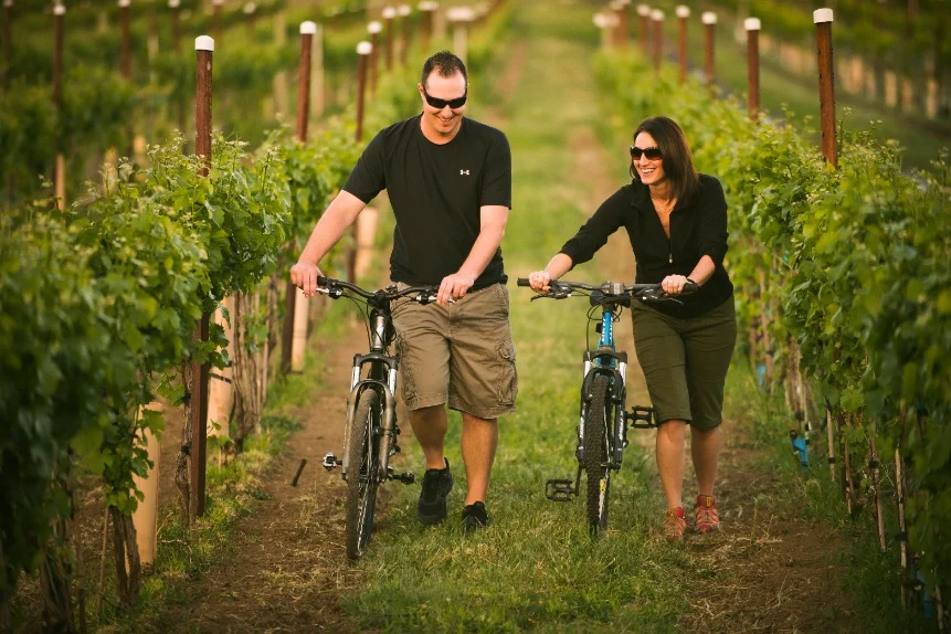 Man en vrouw lopen met hun fietsen aan de hand door rijen wijnstokken in de Yakima Valley in de staat Washington