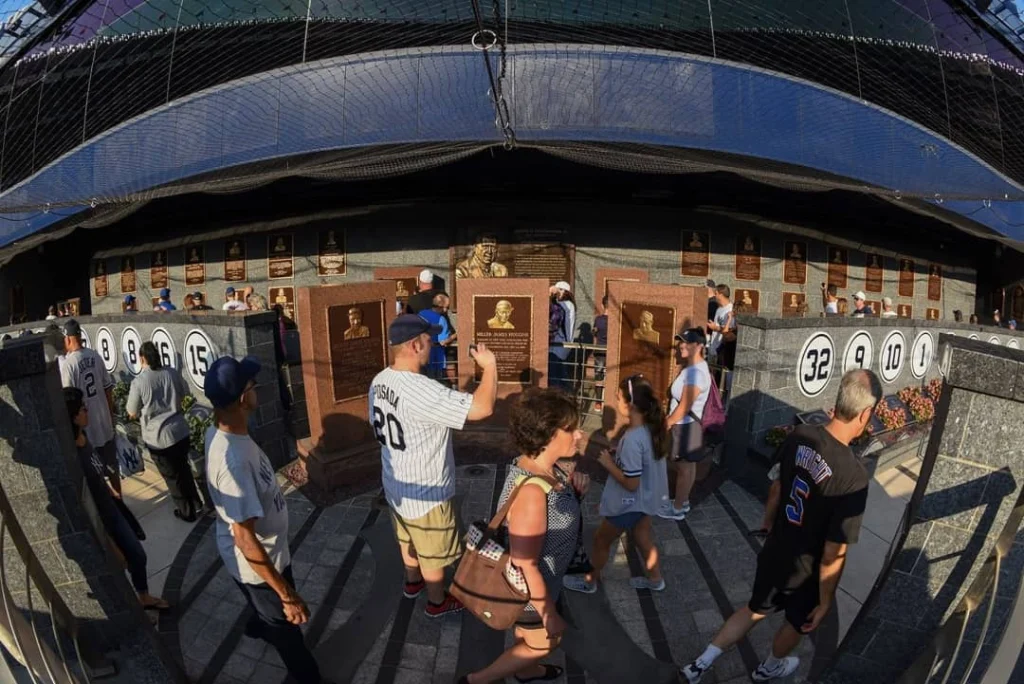 Bezoekers bekijken de gedenkplaquettes en retired rugnummers van legendarische spelers in Monument Park bij Yankee Stadium