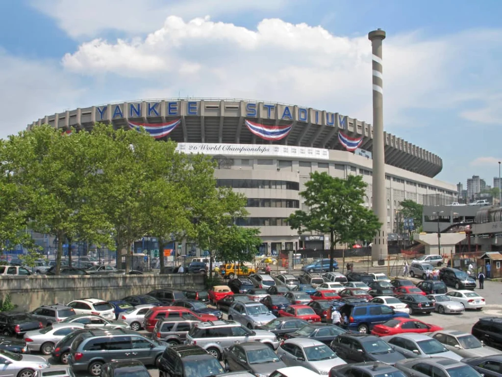 Gevel van Yankee Stadium met de tekst Yankee Stadium en een vol parkeerterrein op de voorgrond overdag