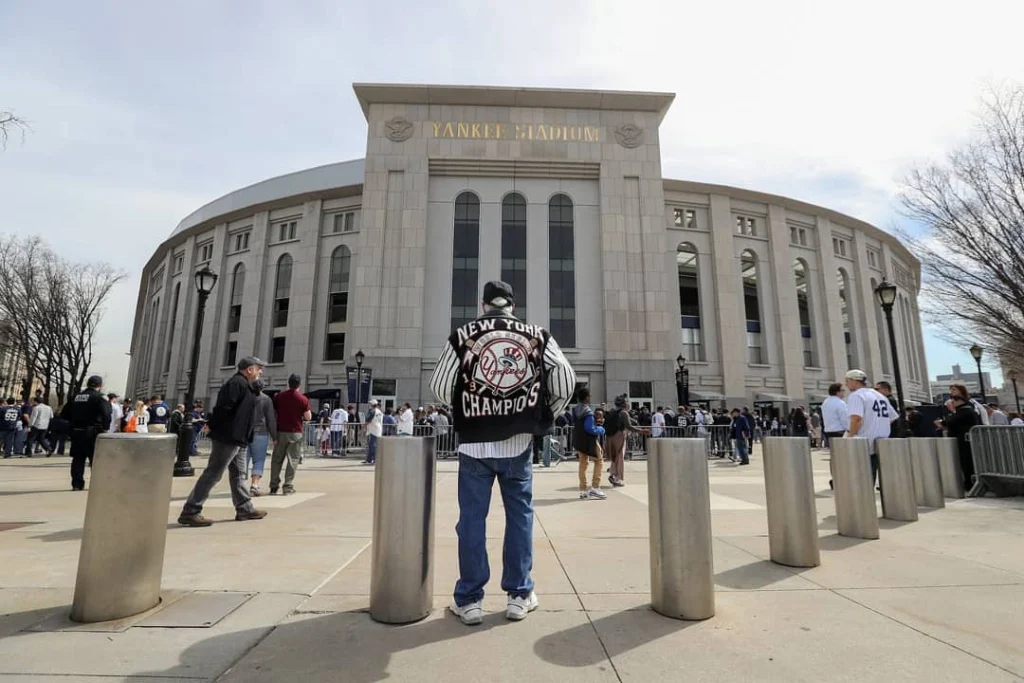 Fan in een zwart witte New York Yankees champions jack staat tussen de stalen palen voor de ingang van het stadion
