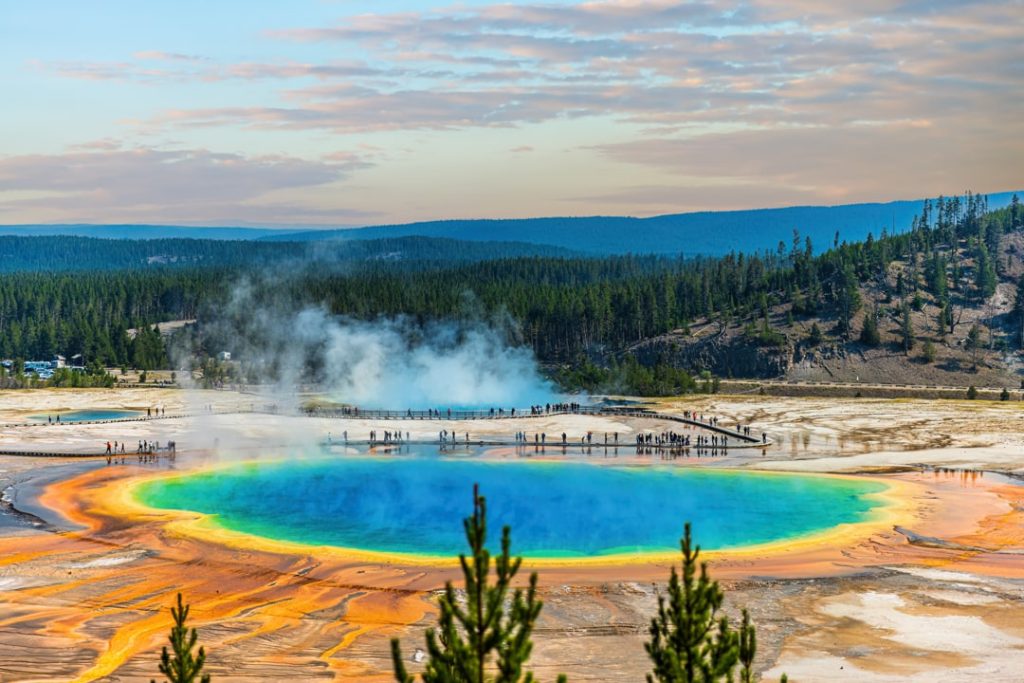Kleurrijke hete bron met een blauwe kern omringd door oranje en gele banden stoom in Yellowstone National Park