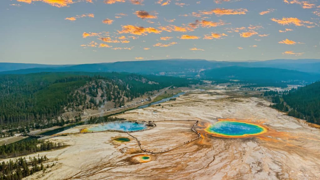 Luchtfoto van de kleurrijke hete bron Grand Prismatic Spring omringd door bos en stoom in Yellowstone National Park bij zonsopkomst