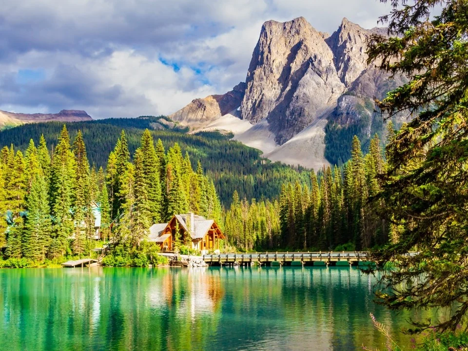 Een houten lodge met steiger aan het smaragdgroene water van Emerald Lake, omringd door dennenbos en steile bergtoppen in Yoho National Park