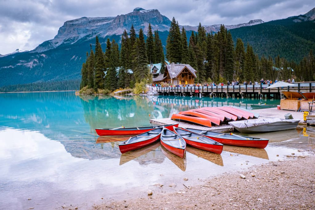 Rode kano's liggen op de oever van het turquoise Emerald Lake met een houten lodge en bergen op de achtergrond