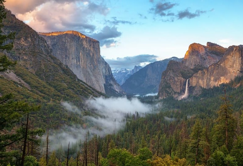 Uitzicht vanaf Tunnel View over een mistige Yosemite Valley met El Capitan, Half Dome en de Bridalveil waterval in gouden ochtendlicht