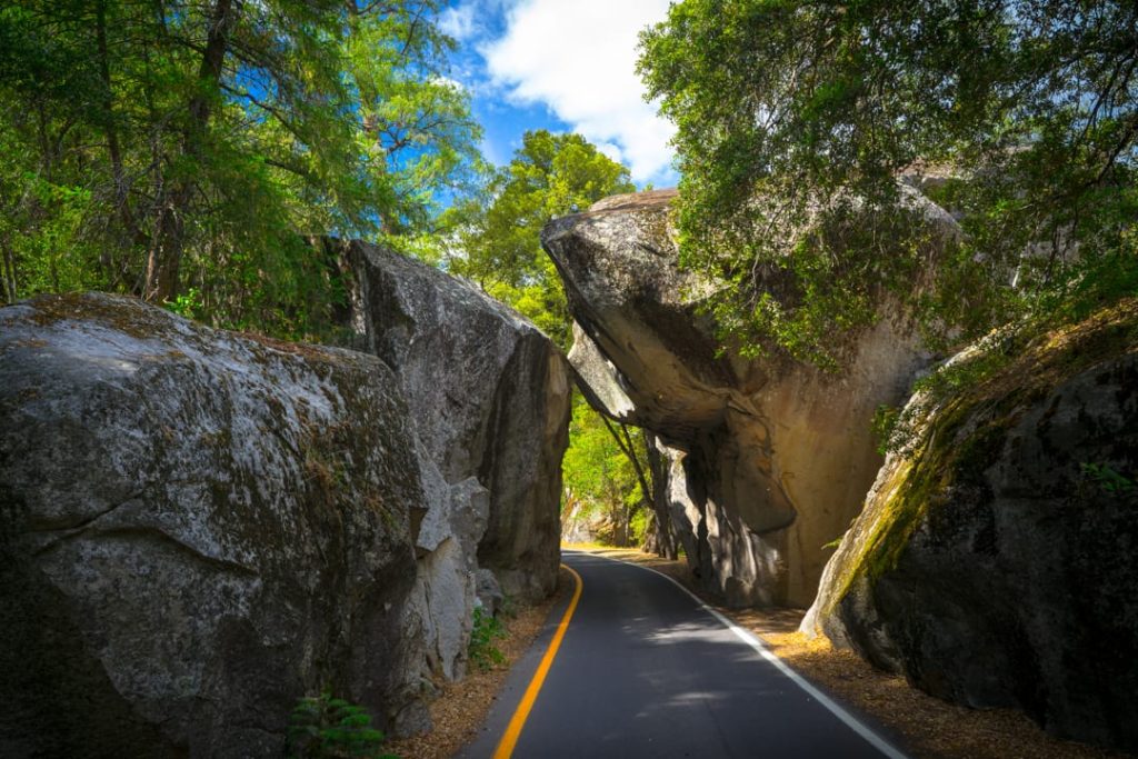Smalle bosweg loopt tussen twee enorme granieten rotsblokken bij de ingang van Yosemite National Park