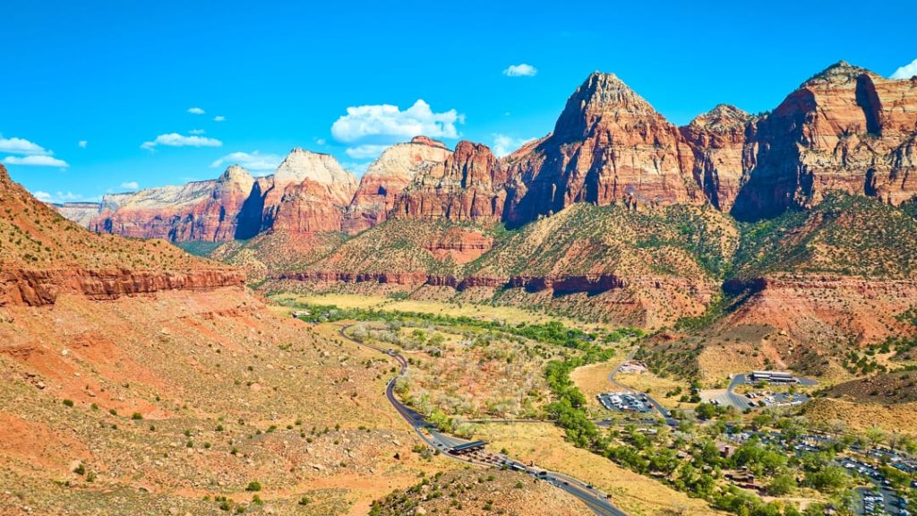 Uitzicht over de groene vallei en rode rotsformaties van Zion Canyon met het bezoekerscentrum in de verte