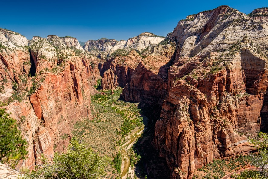Diepe canyon met een groene vallei en rivier omringd door hoge rode en witte rotsformaties in Zion National Park