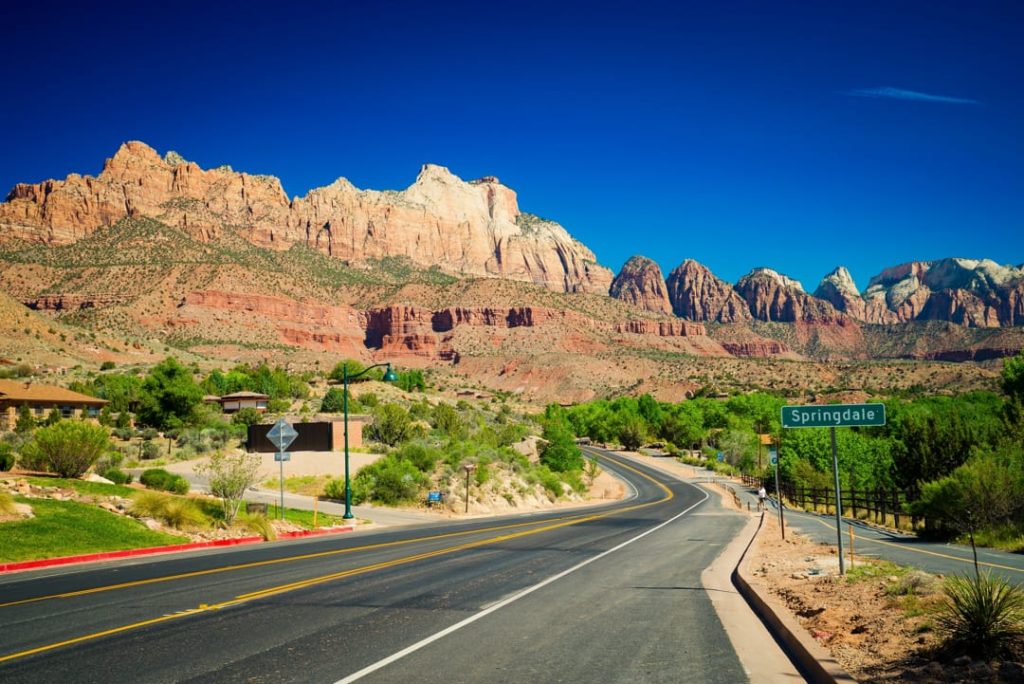 Lege weg met een bord naar Springdale voor een achtergrond van hoge rode en witte rotsformaties in Zion National Park