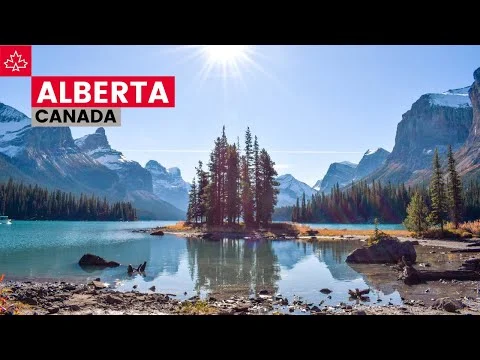 Een klein eilandje met dennenbomen in een turquoise meer, omringd door besneeuwde bergen in Alberta, Canada