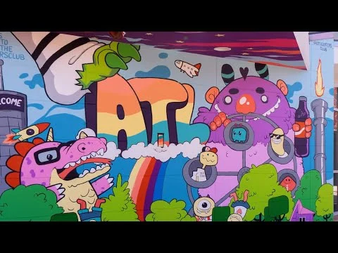 Kleurrijke muurschildering in Atlanta met een dinosaurus, monster en regenboog tussen cartoonfiguren