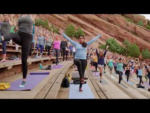 Videothumbnail met een grote groep mensen die yoga doet op de trappen van het amfitheater Red Rocks