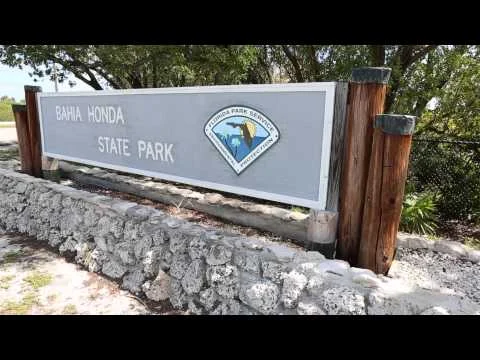 Een grijs ingangsbord met opschrift Bahia Honda State Park tussen houten palen en koraalstenen in de Florida Keys