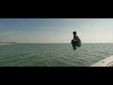 Een man maakt een sprong vanaf een boot in het turquoise water nabij Fort Myers en Sanibel in Florida