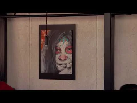 Ingelijst schilderij van een gezicht hangt aan een lichte wand in een interieur, still uit een video over Idaho
