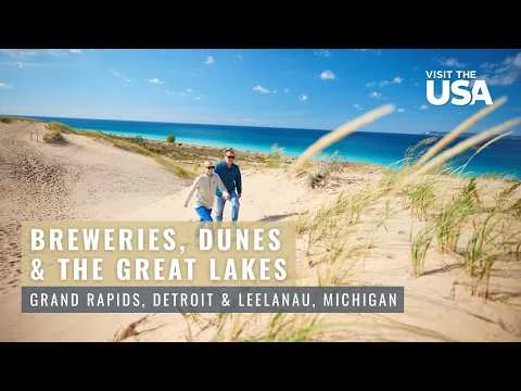 Man en vrouw lopen samen over zandduinen met helmgras langs het turquoise water van Lake Michigan in Leelanau