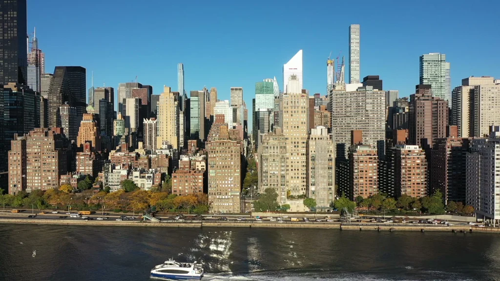 Luchtfoto van hoge appartementengebouwen en kantoortorens van Manhattan langs de oever van de rivier, met een bootje op het water