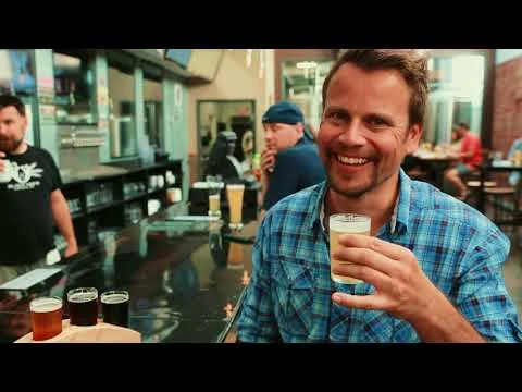 Lachende man houdt een glas bier vast aan een bar in een brouwerij, still uit een video over Montana