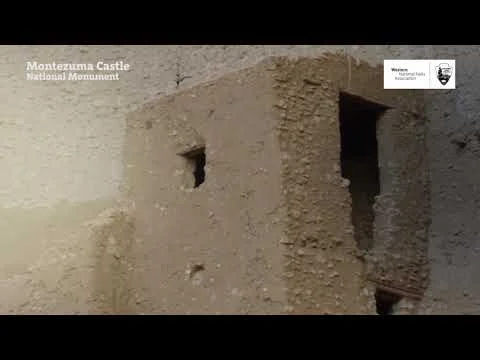 Videostilstaand beeld met de tekst Montezuma Castle National Monument over een close-up van de ruwe kleien stenen muur van de cliffdwelling