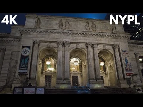 Verlichte gevel van de New York Public Library bij avond met promotiebanieren tussen de zuilen