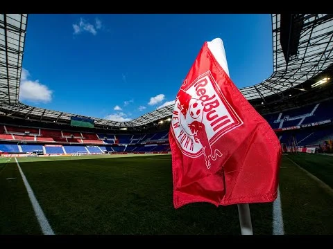 Rode hoekvlag met het Red Bull New York logo op het veld van Red Bull Arena tegen een blauwe lucht